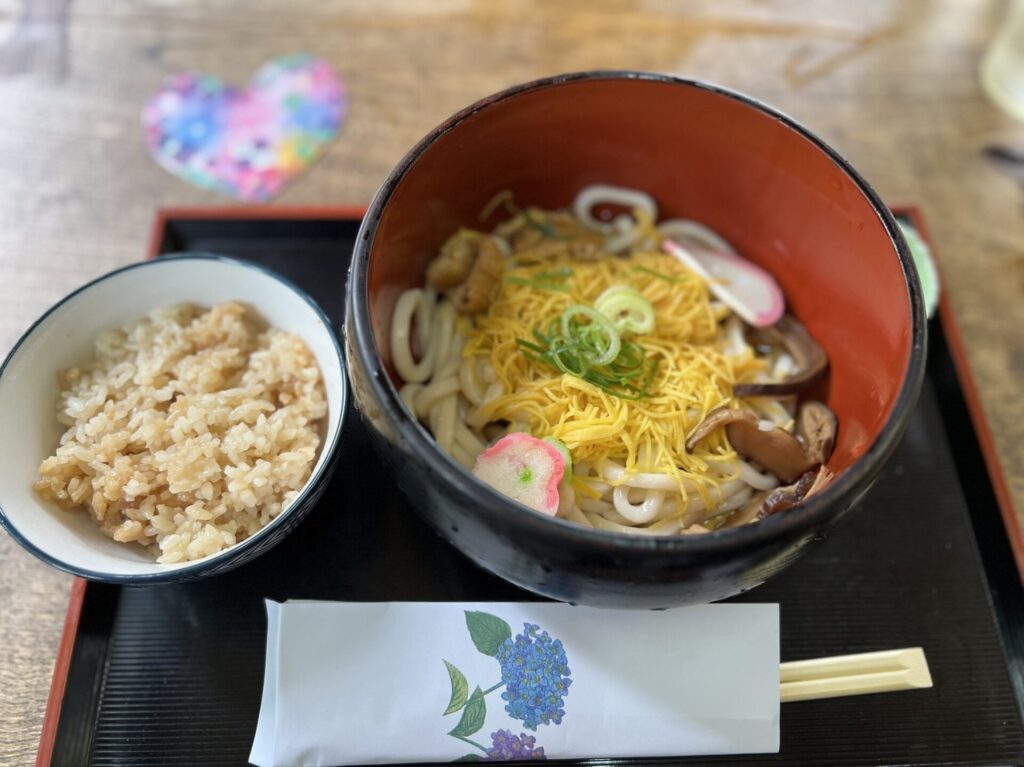 A hearty udon set at the seasonal teahouse inside Mimurotoji temple — topped with shredded egg, mushrooms, kamaboko, and green onion, served with a side of takikomi gohan.